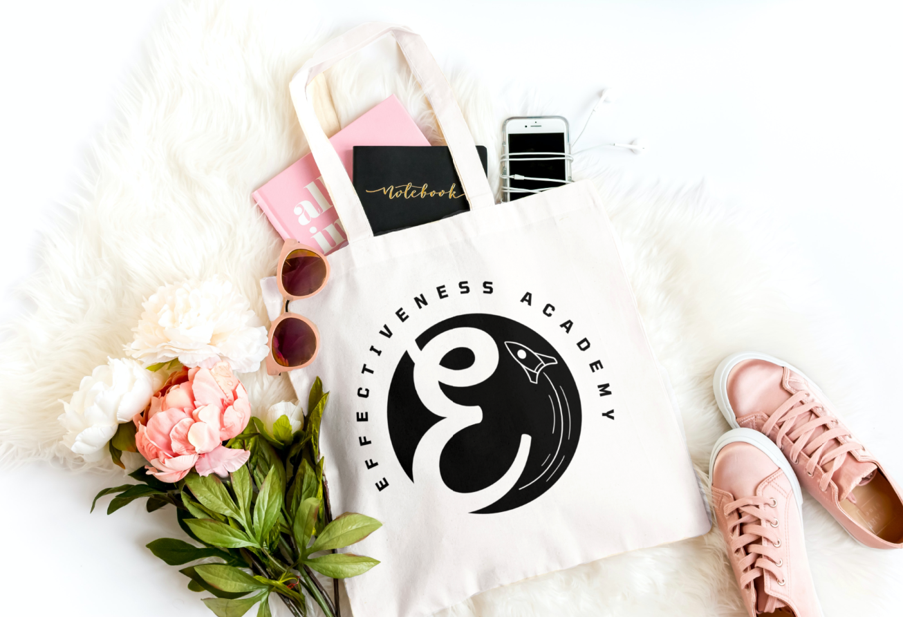 Digital Product Academy-branded Canva bag bursting with productivity tools: assorted books on digital strategy, planners for goal-setting and tracking progress, and an iPhone showcasing the latest in tech integration. The logo of the Academy prominently displayed on the side of the bag signifies quality education for aspiring digital marketers. Perfect visual representation of the tools needed to optimize your effectiveness efforts..