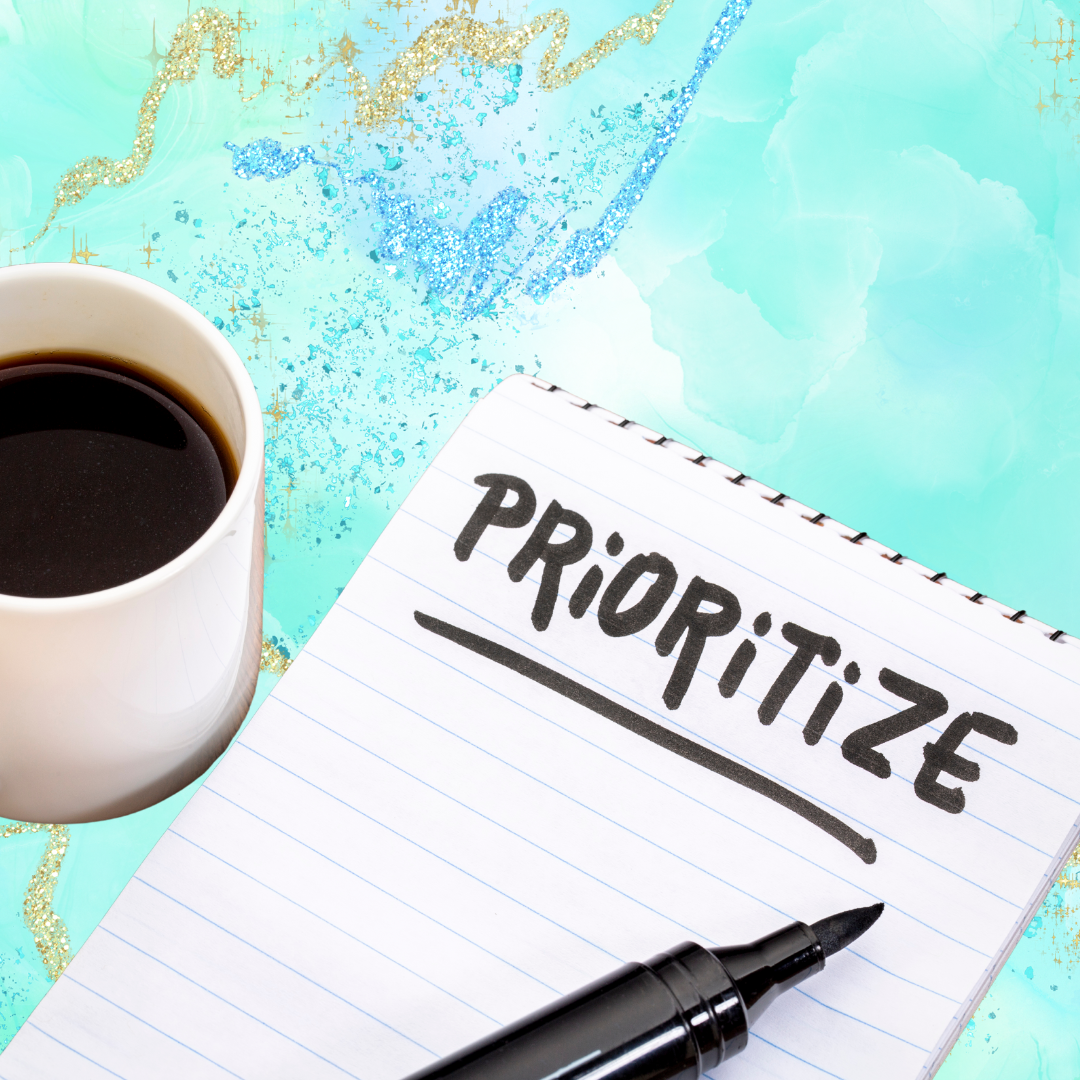 a notepad with written: "prioritize" on it, marker and a cup of coffee on pastel green background